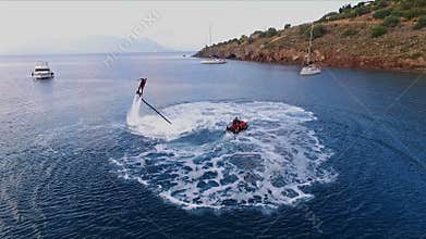 The man is having fun, flying over the water on a flyboard, under the pressure of water. Aerial video shooting, bird`s
