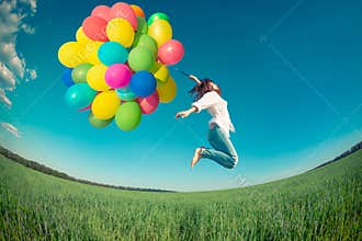 Woman jumping with toy balloons in spring field