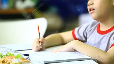 Asian boy doing homework at home .