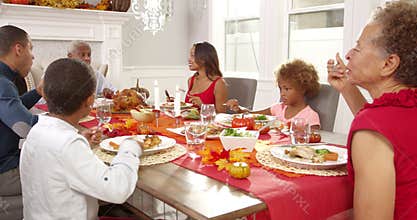 Camera tracks down to show extended family sitting around table for Thanksgiving meal