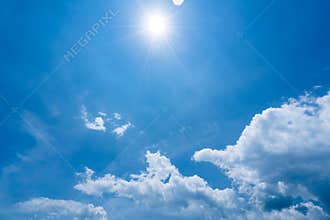 Bright sunshine with sun flares and clouds on clear blue sky background, hot summer concept