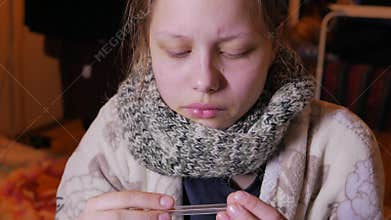Teen girl having a flu or cold. Using thermometer, 4K UHD