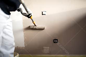 Man decorating walls with paint. Construction plaster worker painting and renovating with professional tools