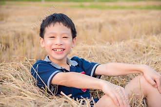 Boy smiling in hay after rice field cultived