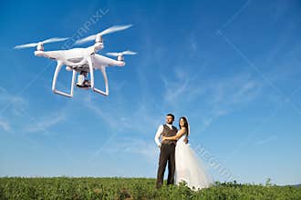 Hovering drone taking pictures of wedding couple in nature