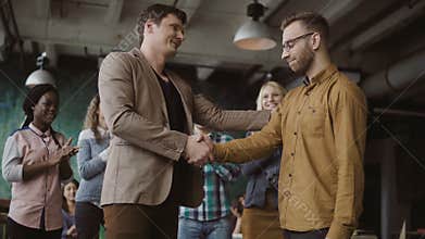 Two partners, businessman shake hands. Group of people clapping on a background. Manager congratulates trainee promotion