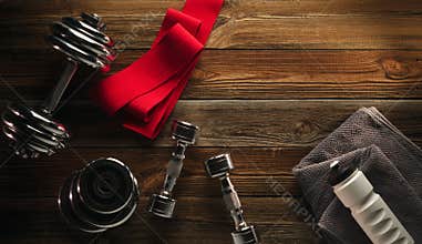 Top view Fitness equipment and supplements on wooden floor in gym Fitness background with Pair of Sneakers Grey Towel Water