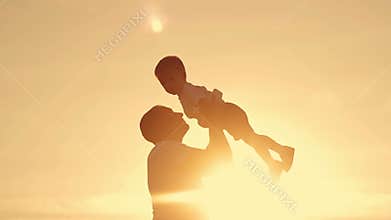Silhouette of dad and son at sunset.