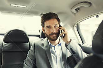 Casual business man on mobile phone in rear of the car