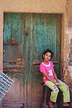 Girl portrait sitting by an old wooden door