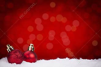 Red Christmas baubles on snow with a red background