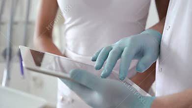 Close up of dentist with woman using tablet with xray of teeth