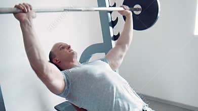 Strong sportsman doing biceps curls with barbell