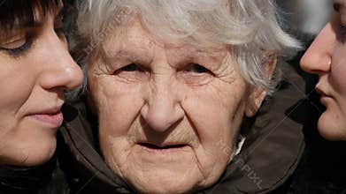Young girl and adult woman kissing grandmother on cheeks, Granny smiling and looking to the camera.