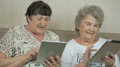 Two old women holding the silver digital tablets