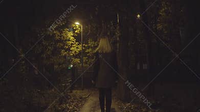 Young blonde woman walking on the street the night