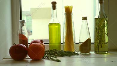 Food ingredients near kitchen window. Cooking oil and kitchen herbs
