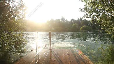 Couple holding hands and jumping into water from river dock