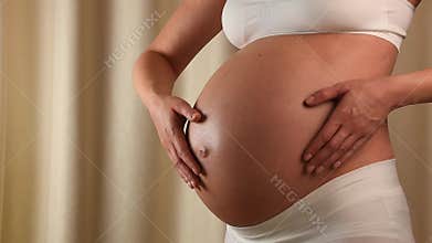 Pregnant woman touching her belly with hands