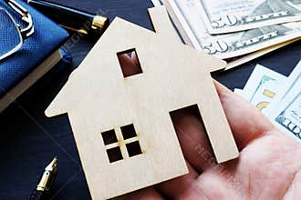 Hand holding model of house. Buying property or mortgage.