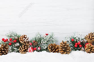 Christmas snow scene. Christmas tree branches with cones and ornaments on wooden light background,