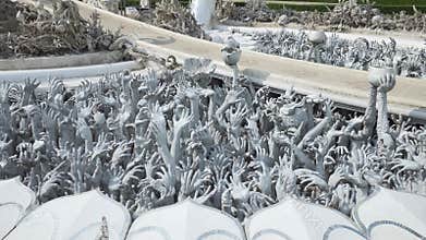 Sculptures of human hands sticking out of the ground. From the hell. Wat Rong Khun.