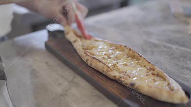 Chef hands grease baked dough of turkish arabic food fatayer with olive oil in modern restaurant kitchen close up