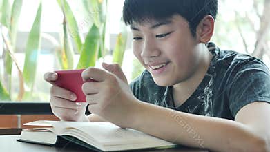 Teenage boy plays games on mobile phone.