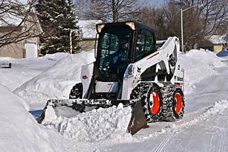 Bobcat skid steer removing snow from driveway