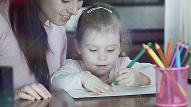 Happy family. Mother and daughter together paint. Adult woman helps the child girl.