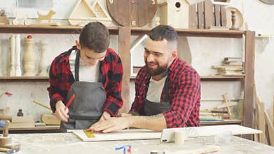 Dad showing video on laptop to his son before working with wood together