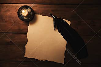 Old paper and quill pen in candlelight. top view