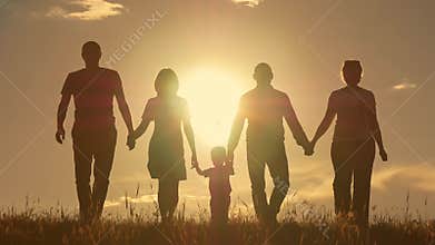 Happy young family with children running around the field, silhouette at sunset