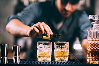 Barman adding cocktail ingredients on whiskey cocktails at the bar