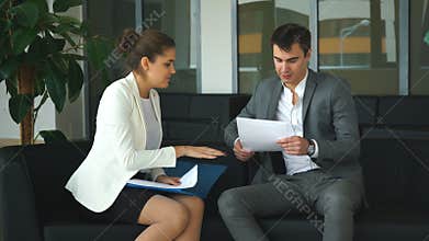 Two colleagues discussing business ideas sitting on the chairs in the office