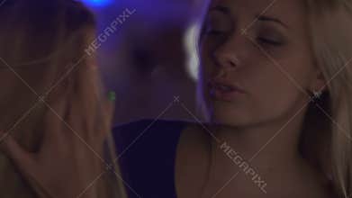 Best friends talking about problems in nightclub, one being consoled by another