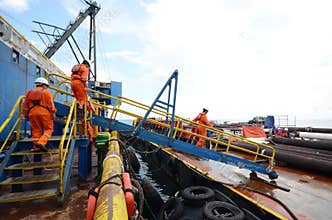 Construction crews crossing gangway to cargo barge