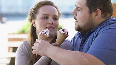 Obese loving couple sharing ice-cream, sugary sweet dessert, flirting on date