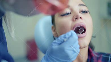 Dentist examining patient teeth using mirror in clinic