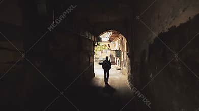 Unidentified silhouette of strange man walking through dark alleys in city