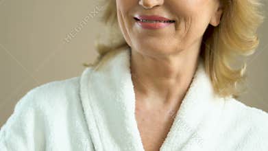Healthy and happy middle-aged woman with smile looking at reflection in mirror