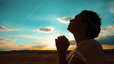 Girl praying. Girl folded her hands in prayer silhouette at sunset. slow motion video. Girl folded her hands in prayer