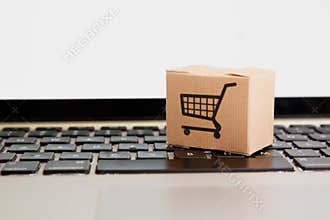 Online shopping . ecommerce and delivery service concept : Paper cartons with a cart or trolley logo on a laptop