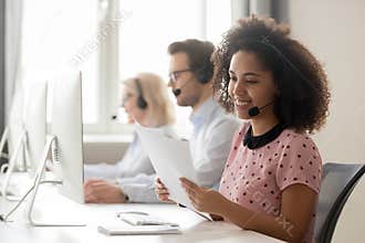 Smiling african woman call center operator wearing headset reading papers