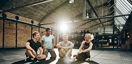 Smiling friends sitting and talking together after a gym workout