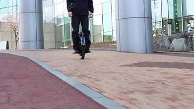 An office worker is driving on an electric mono wheel near the business center
