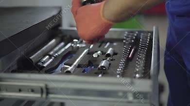 Close up hands of mechanic in gloves take the tool out of the box and collects parts together. Worker fixing automobile