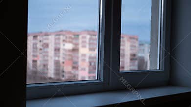 From Day to Night View through the Window at the Lights the Windows in High-rise Buildings