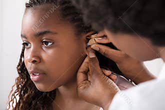 Doctor Putting Hearing Aid In Patient`s Ear