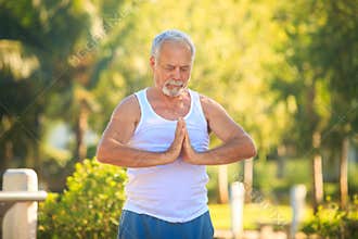 Grey Bearded Old Man in White Vest Shows Yoga in Park